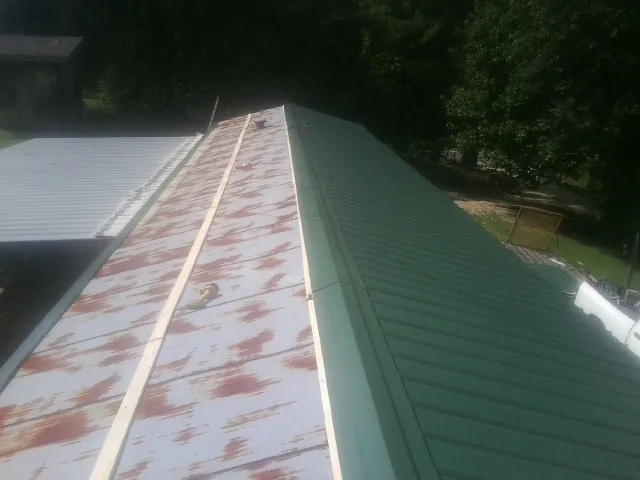 Old rusted panels beside newly installed green metal roofing — Wind Damage Roof Repair by Roofing Brothers in Clarkson