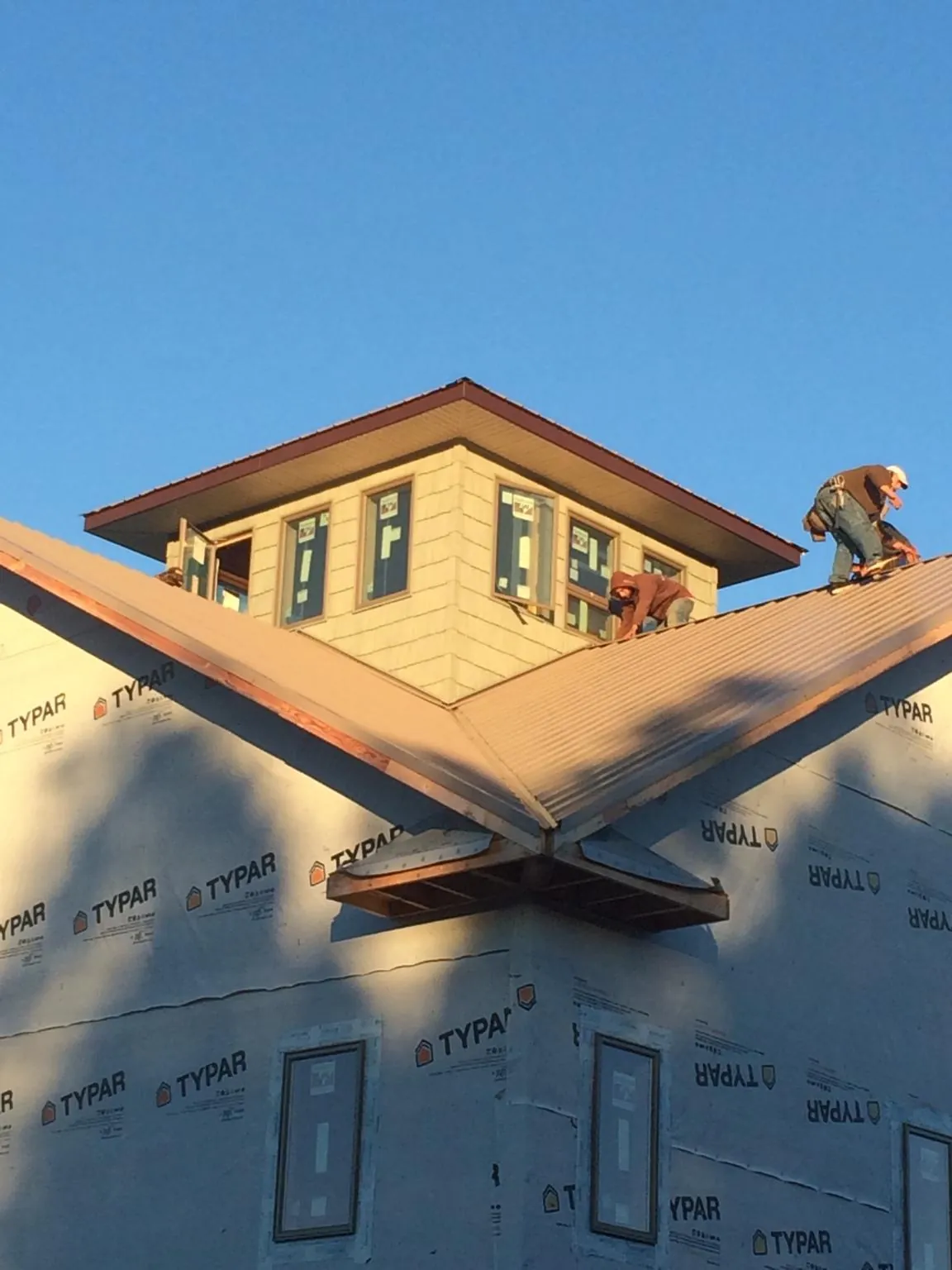 Roofers working around a rooftop cupola on a new metal roof at sunset — Roof Waterproofing in Clarkson by Roofing Brothers